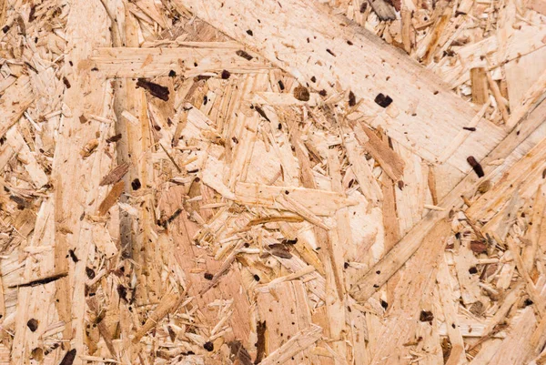 OSB boards are made of brown wood chips sanded into a wooden background. Top view of OSB wood veneer background, tight, seamless surface. Oriented Strand Board. Flake board. Sterling board. Aspenite