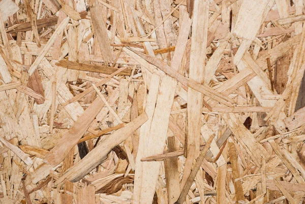 OSB boards are made of brown wood chips sanded into a wooden background. Top view of OSB wood veneer background, tight, seamless surface. Oriented Strand Board. Flake board. Sterling board. Aspenite