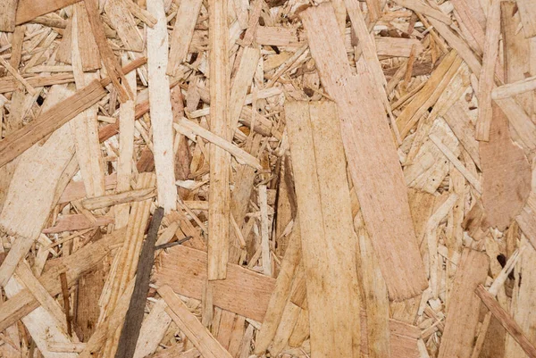 OSB boards are made of brown wood chips sanded into a wooden background. Top view of OSB wood veneer background, tight, seamless surface. Oriented Strand Board. Flake board. Sterling board. Aspenite