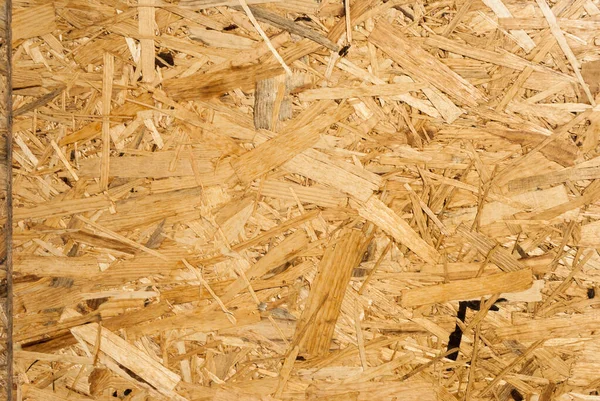 OSB boards are made of brown wood chips sanded into a wooden background. Top view of OSB wood veneer background, tight, seamless surface. Oriented Strand Board. Flake board. Sterling board. Aspenite