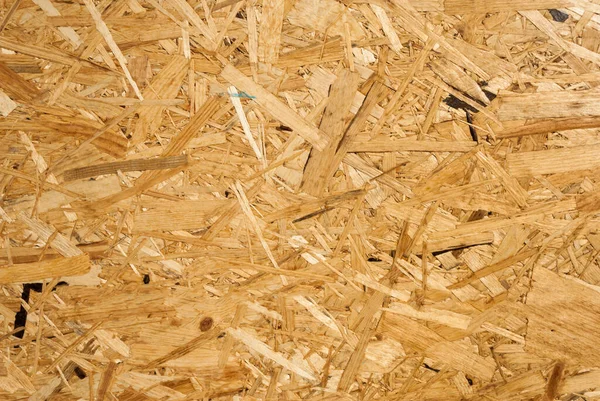 OSB boards are made of brown wood chips sanded into a wooden background. Top view of OSB wood veneer background, tight, seamless surface. Oriented Strand Board. Flake board. Sterling board. Aspenite