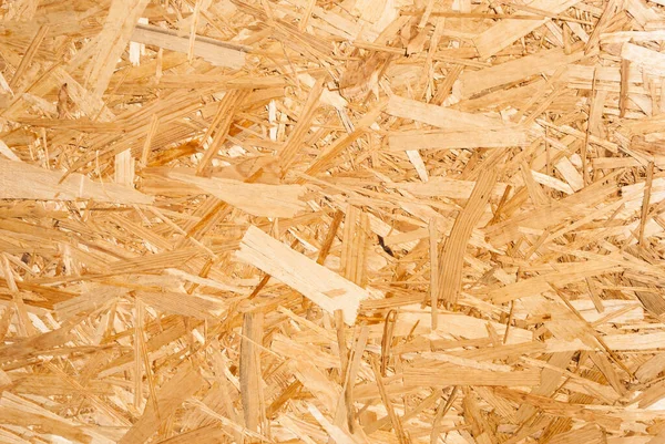 OSB boards are made of brown wood chips sanded into a wooden background. Top view of OSB wood veneer background, tight, seamless surface. Oriented Strand Board. Flake board. Sterling board. Aspenite