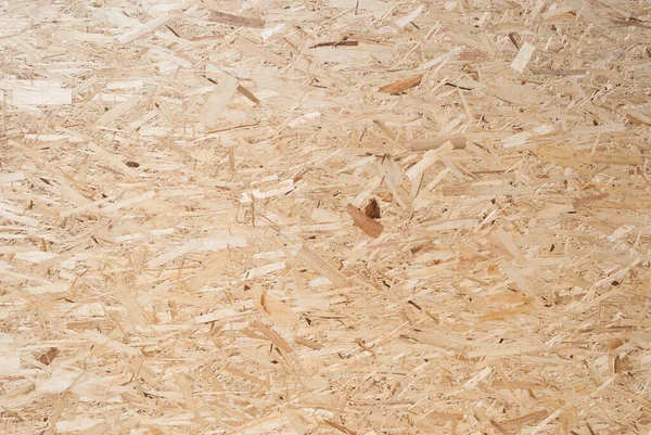 OSB boards are made of brown wood chips sanded into a wooden background. Top view of OSB wood veneer background, tight, seamless surface. Oriented Strand Board. Flake board. Sterling board. Aspenite