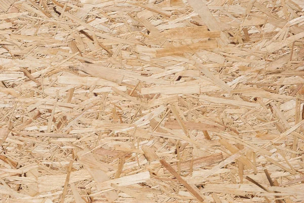 OSB boards are made of brown wood chips sanded into a wooden background. Top view of OSB wood veneer background, tight, seamless surface. Oriented Strand Board. Flake board. Sterling board. Aspenite