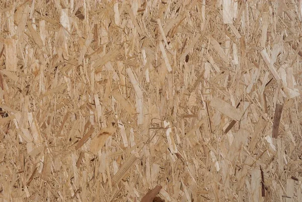 OSB boards are made of brown wood chips sanded into a wooden background. Top view of OSB wood veneer background, tight, seamless surface. Oriented Strand Board. Flake board. Sterling board. Aspenite