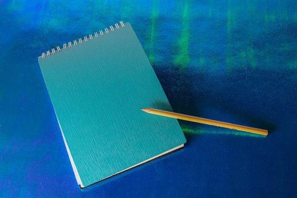 Mavi masadaki defter ve kalem.