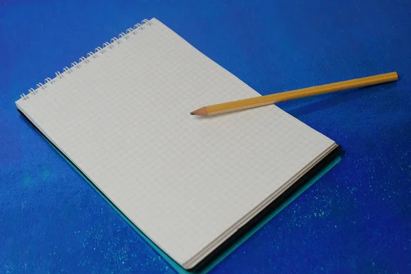 Mavi masadaki defter ve kalem.