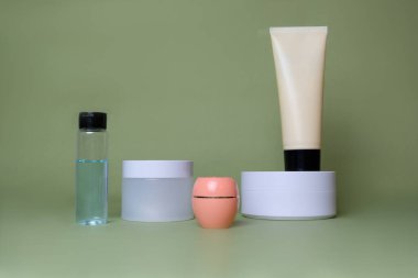 Yeşil arka planda kozmetik ürünleri olan kavanozlar