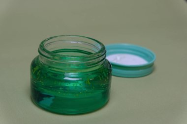 Yeşil arka planda yeşil aloe jeli küçük kavanoz