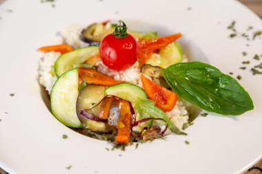 Beyaz bir tabak taze sebze ve pirinç ile. Vegan taze yiyecek. Kekik ile süsleyin ve üst bir kiraz domates.