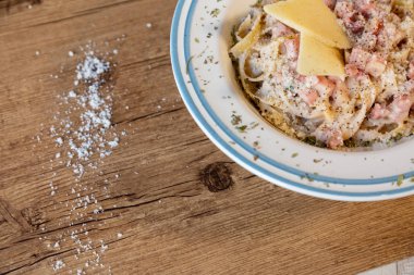 Peynir, pastırma ve biber ile ahşap bir masa carbonara spagetti tabağına bir ayrıntı