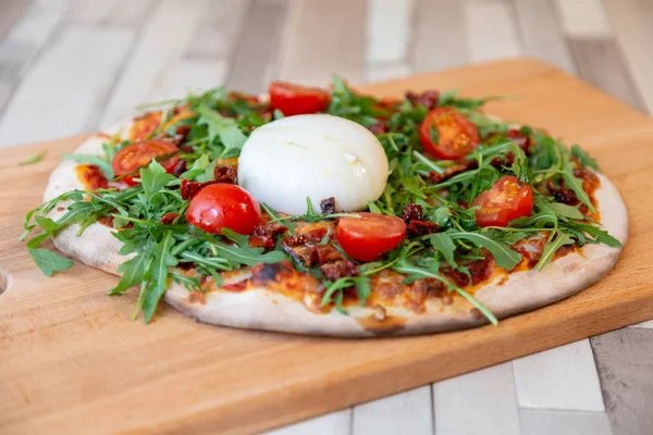 pizza domates, roka ve ahşap bir masa üzerinde burrata peynir ile ahşap bir gemide