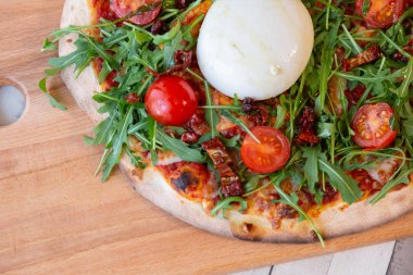 Bir Pizza domates, roka ve ahşap bir masa üzerinde burrata peynir ile ahşap bir gemide yakın çekim