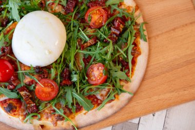 Bir Pizza domates, roka ve ahşap bir masa üzerinde burrata peynir ile ahşap bir gemide yakın çekim