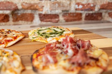 bir tuğla duvar ile ahşap bir masa pesto pizza odakta ile ahşap bir gemide pizza