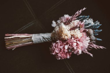 karanlık bir arka plan üzerinde beyaz, mavi ve pembe çiçekli rustik bir gelin buketi