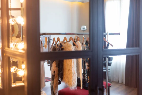 interior of the dressing room of an actress, with a mirror with bulb lights and a rack with clothes
