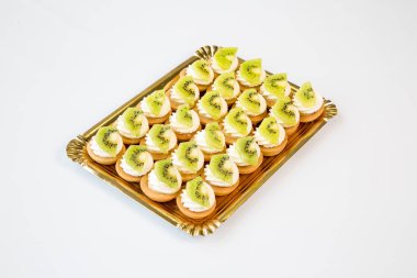 Kivi kek içinde beyaz zemin üzerine altın bir tepsi