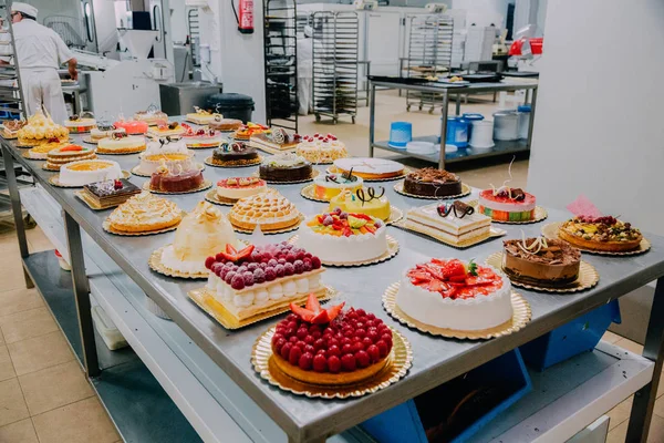 many different cakes prepared on the metal table of a food factory