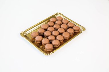 Beyaz arka plan ile altın bir tepsi üzerinde kahverengi Çikolata macaroons