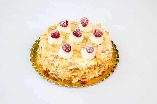 beautiful almond and raspberry cake on a gold tray on white background