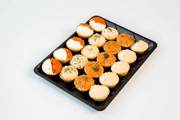 small tasty snacks on a black tray prepared to takeaway on white background