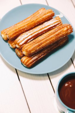 İspanyol börek ve sıcak çikolata Mavi çanak ve ahşap bir masa bardakta servis