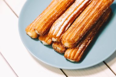 İspanyol şeker börek mavi tabak ahşap bir masa üzerinde yılları arasında görev yapmıştır