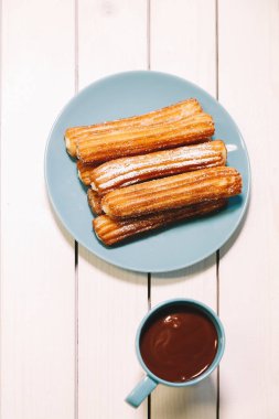 İspanyol börek ve sıcak çikolata Mavi çanak ve ahşap bir masa bardakta servis