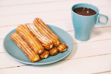 İspanyol börek ve sıcak çikolata Mavi çanak ve ahşap bir masa bardakta servis