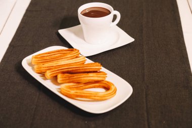 İspanyol börek gri masa örtüsü ve sıcak çikolata bir fincan ile ahşap bir masada hizmet