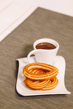 İspanyol börek gri masa örtüsü ve sıcak çikolata bir fincan ile ahşap bir masada hizmet