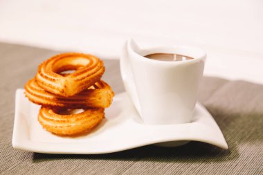 İspanyol börek gri masa örtüsü ve sıcak çikolata bir fincan ile ahşap bir masada hizmet