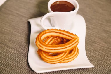 İspanyol börek gri masa örtüsü ve sıcak çikolata bir fincan ile ahşap bir masada hizmet