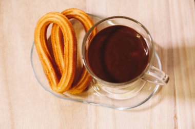 sıcak çikolata ve iki İspanyol börek ile bir cam fincan ahşap tahta üzerinde hizmet