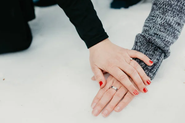 Las manos de una pareja en la nieve con anillos — Foto de Stock