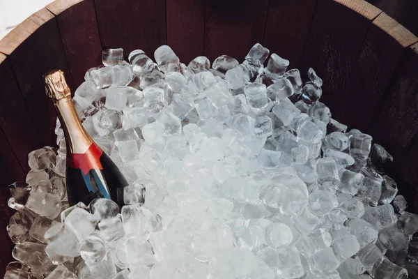 A bottle of champagne in a wooden barrel with ice — Stock Photo, Image
