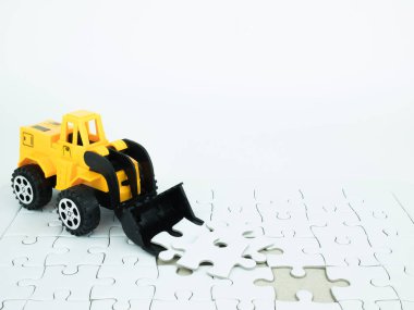 Beyaz zemin üzerine parçalı bulmaca ile oyuncak buldozer.