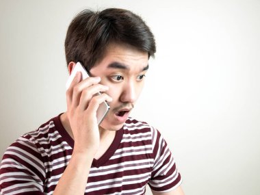 Genç Asyalı adam konuşmak smartphone ve duygu şok ve gri arka plan ile sürpriz.