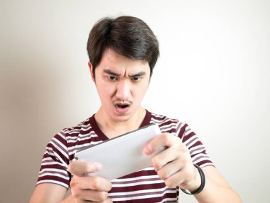 Genç ciddi adam akıllı telefon gri arka plan üzerinde oyun.