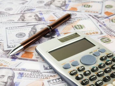 Bu arka plan olarak yüz dolarlık banknot yığın hesap makinesi ve kalem ile çok.