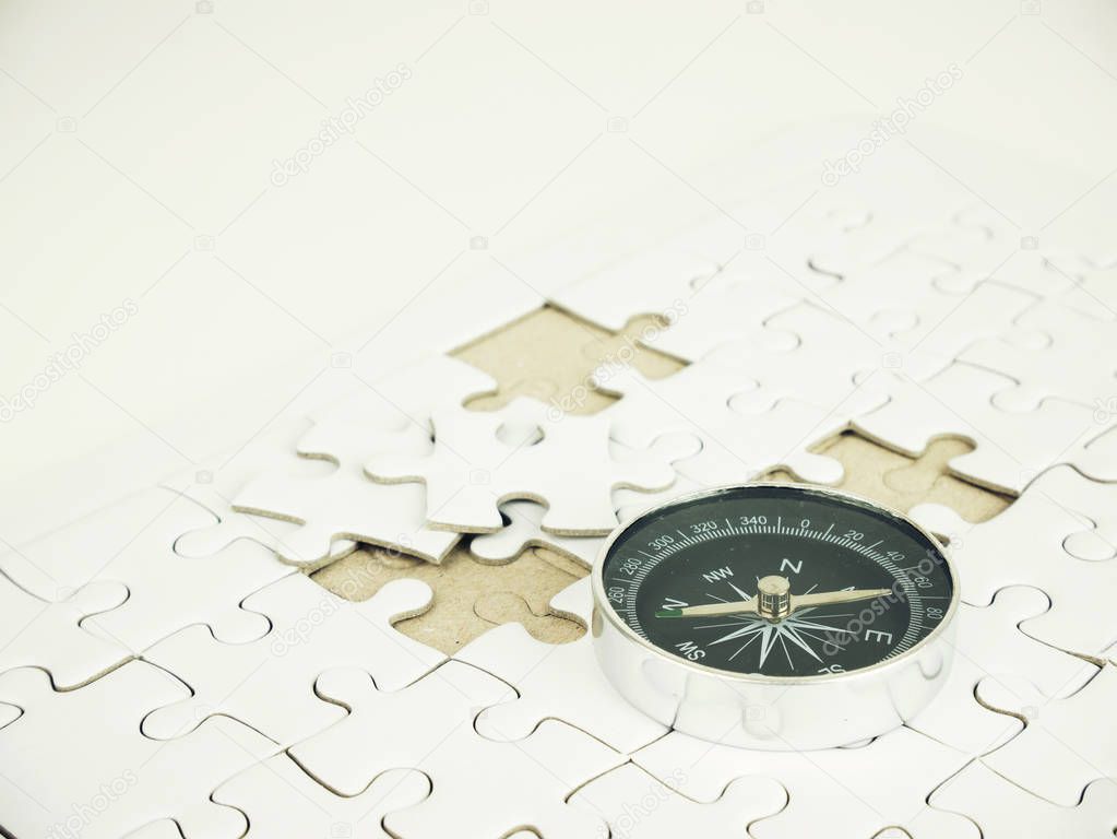 Compass on jigsaw puzzle background, business concept.