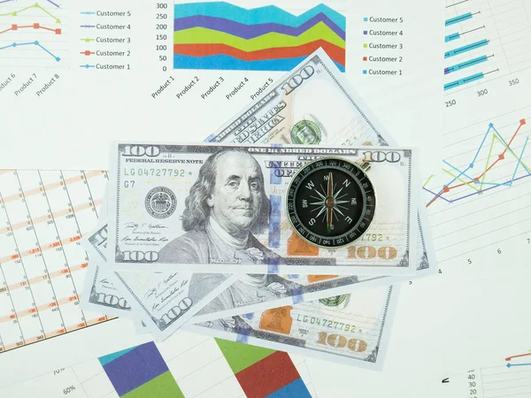 Business report chart and Financial graph analysis with dollar money and compass on table.