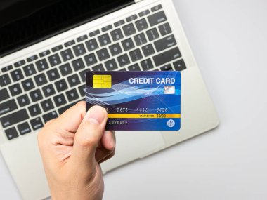 Bilgisayarı ve el ele tutuşan modern beyaz ofis masası çevrimiçi alışveriş için kredi kartı kullanıyor..