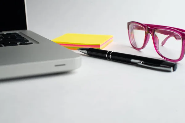 Notebook with black pen, Colorful notepads on the desk, Glasses on the desk with pen and cup of coffee, Computer keyboard with colorful note stick