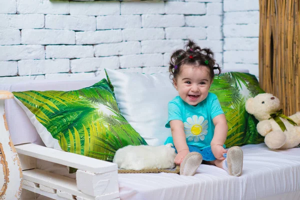 Mutlu gülümseyen tatlı bebek kız ayı oyuncak ile kanepede oturan