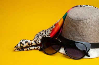 Yaz aksesuarları, şapka ve güneş gözlüğü sarı arka plan üzerinde. Su