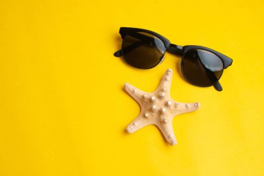 Sarı backgrou üzerinde yaz aksesuarları, deniz kabuğu ve güneş gözlüğü