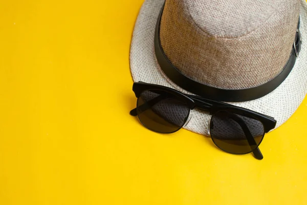 Yaz aksesuarları, şapka ve güneş gözlüğü sarı arka plan üzerinde. Su