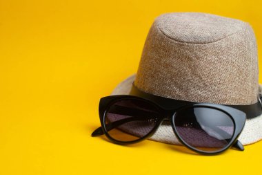 Sarı backgro üzerinde yaz aksesuarları, panama şapka ve güneş gözlüğü